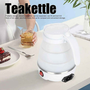 White foldable electric teakettle on table with glass of tea and dessert