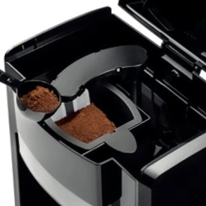Coffee maker with open lid and ground coffee in a scoop and filter basket