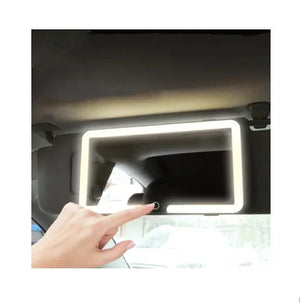 Hand touching car sun visor vanity mirror with LED light in interior view
