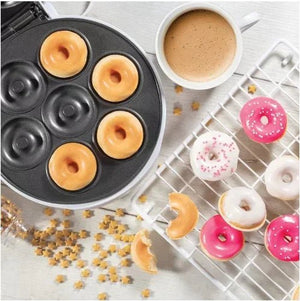 Mini donuts in a donut maker, coffee cup, and decorated donuts on a cooling rack