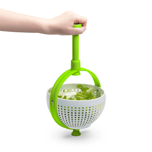 Hand holding green and white salad spinner strainer with lettuce inside