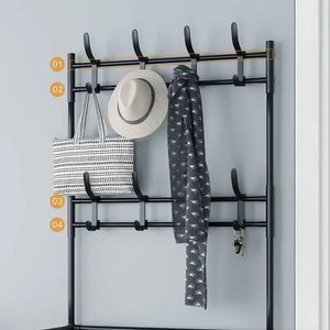 Black metal wall-mounted coat rack with hooks holding a hat, scarf, tote bag, and keys