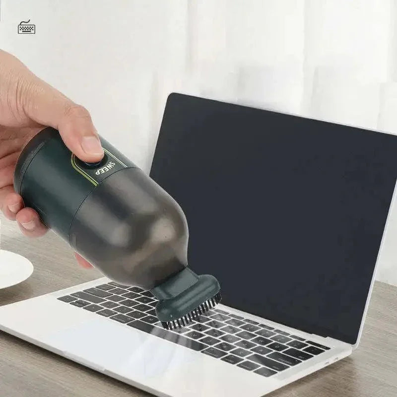 Hand using a mini keyboard vacuum cleaner on a laptop keyboard