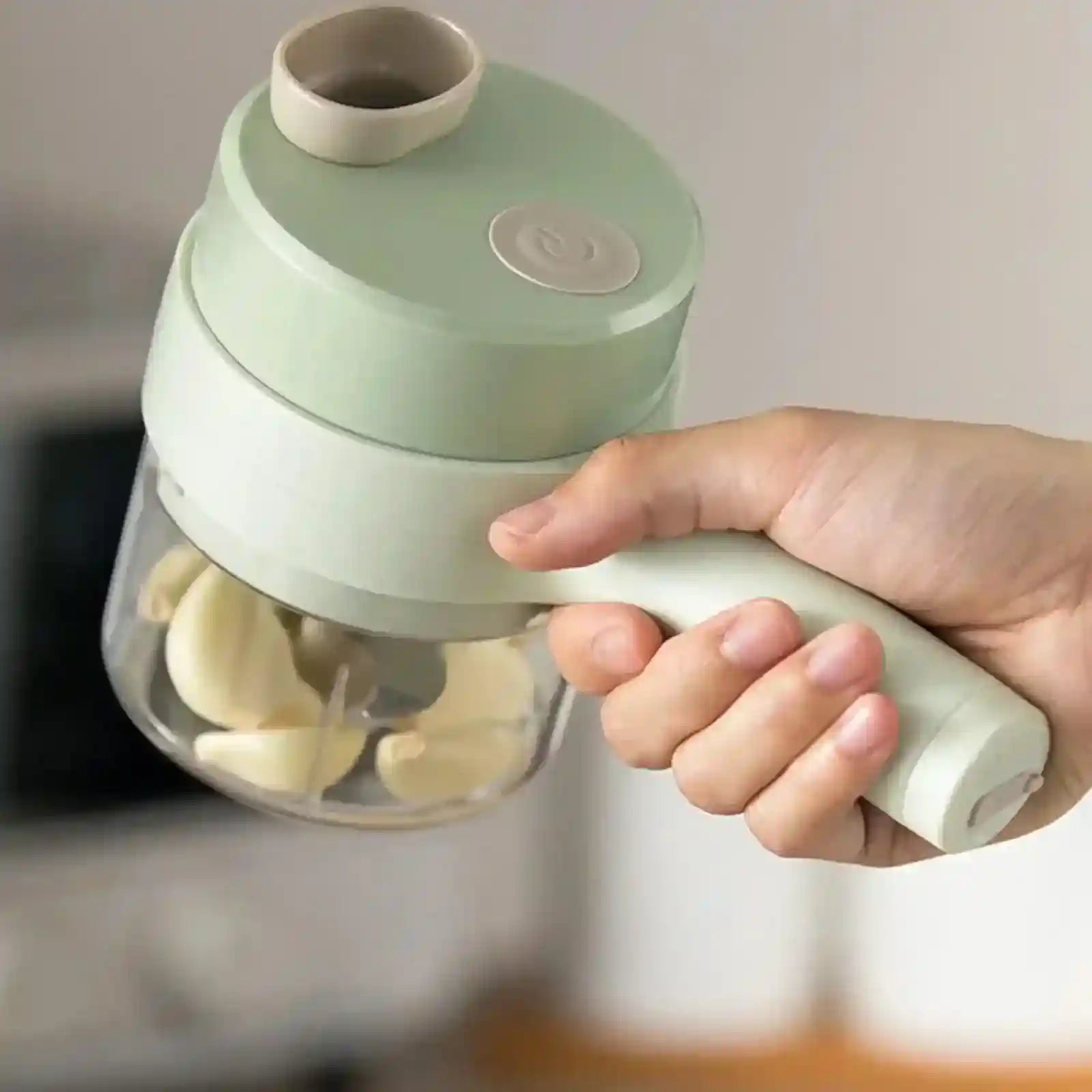 Hand holding 4-in-1 handheld electric vegetable cutter with garlic cloves inside
