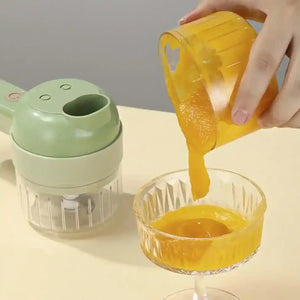 Handheld electric vegetable cutter with blended orange puree being poured into glass bowl