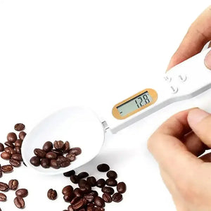 Digital spoon scale measuring coffee beans on a white background