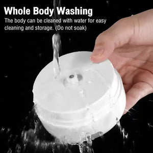 Hand washing a white round electronic device under running water against a black background