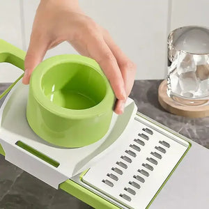 Hand using green vegetable slicer on kitchen countertop, close-up of grater blades