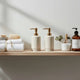 Minimalist bathroom shelf with towels, soap, pumps, body wash, conditioner, and bath essentials