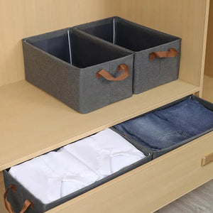 Gray fabric storage bins with leather handles in wooden closet, organizing clothes