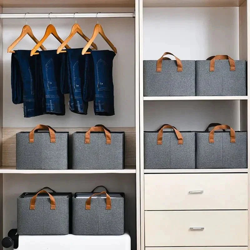 Organized closet with hanging jeans and gray storage bins with brown handles
