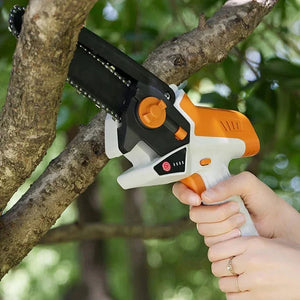 Handheld mini electric chainsaw trimming tree branch outdoors